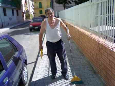 Il signor Pasquale Cangiano, armato di scopa e paletta, spazza fuori casa sua